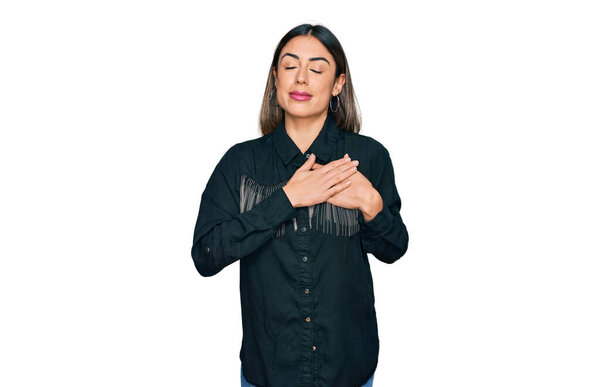 Молодая латиноамериканка в повседневной одежде улыбается с закрытыми глазами на груди и благодарным жестом на лице. концепция здоровья. 