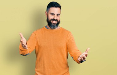 Sakallı, sıradan bir kazak giyen, gülümseyen, yardım eli uzatan ve kabullenen İspanyol bir adam.. 