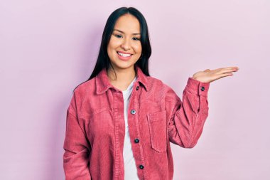 Güzel İspanyol kadın, burun piercing 'i takıyor, pembe ceket giyiyor, gülümsüyor, eli avucunda kameraya bakıyor ve gülümsüyor.. 