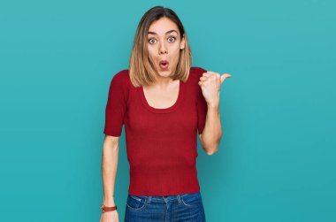 Gündelik kıyafetler giyen genç sarışın kız elleri yana doğru işaret ederek şaşırdı, ağzı açık hayret içinde kaldı.. 