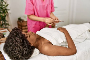 Genç Afrikalı Amerikalı kadın güzellik merkezinde manikür seansı yapıyor.