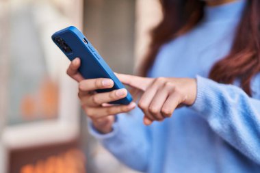 Sokakta akıllı telefon kullanan genç İspanyol kadın.