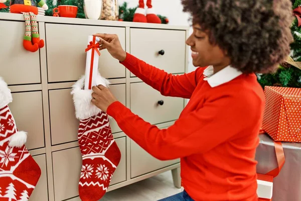 Jovem Afro Americana Inserindo Presente Meia Natal Casa — Fotografia de Stock