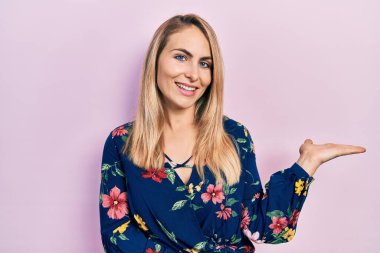 Gündelik kıyafetler giyen, neşeli gülümseyen, avuç içi kameraya bakan beyaz bir kadın.. 