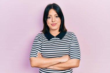 Kollarını kavuşturmuş genç İspanyol kadın yüzünde ciddi bir ifadeyle rahatladı. Basit ve doğal bir şekilde kameraya bakıyorsun.. 