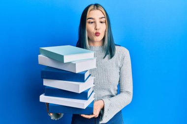 Genç modern kız elinde bir yığın kitap tutarak balık suratlı, şaşı gözlü, çılgın ve komik bakışlar atıyor.. 