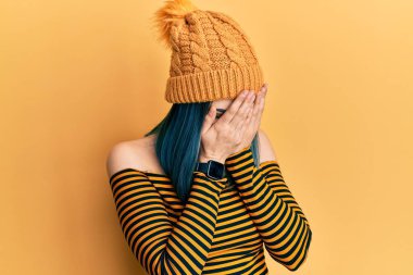 Ağlarken yüzünü ellerle kapatan üzgün ifadeli yün şapka takan genç modern bir kız. depresyon kavramı. 