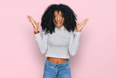 Genç Afro-Amerikan kızı sıradan kıyafetler giyip çılgınlığı kutluyor ve başarıyı kolları açık ve gözleri açık heyecanla haykırarak kutluyor. Kazanan konsept 