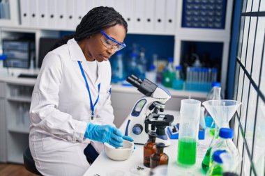 Bilim adamı üniforması giyen Afrikalı Amerikalı kadın laboratuarda çalışıyor.