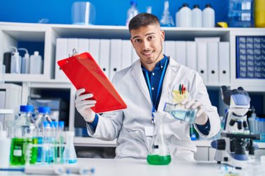 Genç İspanyol bilim adamı laboratuvarda sıvıyı ölçüyor.