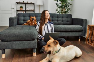 Genç İspanyol kadın dizüstü bilgisayar kullanıyor evde köpeklerle oturuyor.
