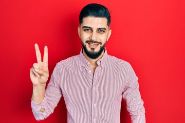 Sakallı, sıradan kırmızı tişörtlü, gülümseyen, kameraya göz kırpan ve zafer işareti yapan yakışıklı adam. İki numara.. 