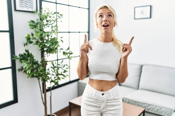 Giovane Donna Caucasica Piedi Soggiorno Stupito Sorpreso Guardando Alto Puntando — Foto Stock