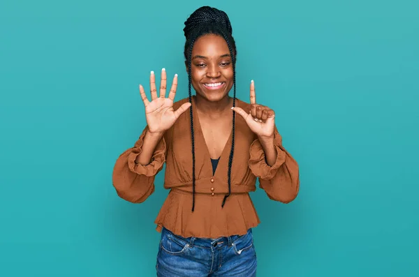 自信を持って幸せな笑顔ながら 若いアフリカ系アメリカ人の女性は カジュアルな服を着て指の番号7で示すと指摘します — ストック写真