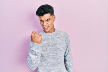 Latin asıllı genç bir adam, kızgın ve kızgın. Öfkeyle bağırırken yumruğunu sallıyor ve öfkeleniyor. öfke ve agresif konsept. 