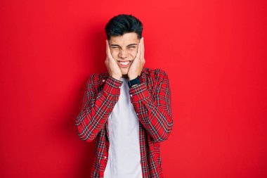 Gürültülü müzik sesi için günlük kıyafetler giyen genç İspanyol adam kulaklarını parmaklarıyla kapatıyor. sağır kavramı. 