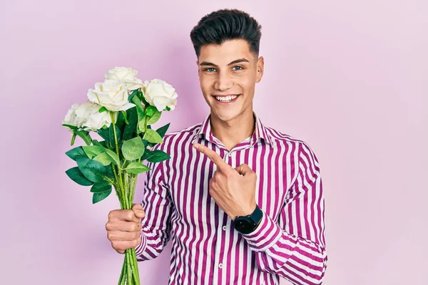 Joven Hombre Hispano Sosteniendo Flores Sonriendo Feliz Señalando Con Mano — Foto de Stock