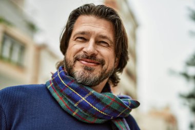 Kasabada gülümseyen orta yaşlı yakışıklı bir adam.