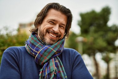 Kasabada gülümseyen orta yaşlı yakışıklı bir adam.