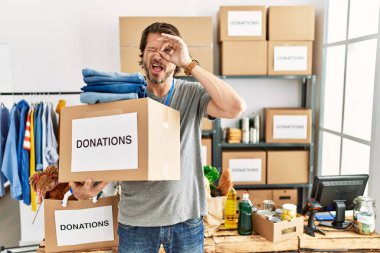 Gönüllü olarak bağış kutusunu tutan yakışıklı orta yaşlı bir adam el hareketleriyle gülümsüyor ve mutlu yüzüyle parmaklarının arasından bakıyor.. 