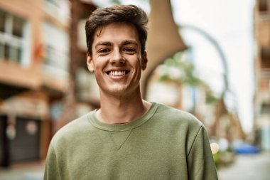 Genç İspanyol adam gülümseyerek şehirde mutlu mesut dikiliyor..