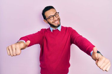 Sakallı, iş gömleği giyen ve gözlüklü İspanyol adam elinle olumlu jest yapıyor, gülümsüyor ve başarı için seviniyor. kazanan jest. 