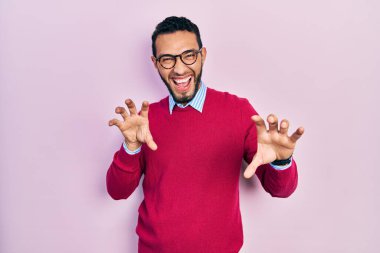 Sakallı, iş gömleği ve gözlüklü, komik gülümseyen, kedi gibi pençeli, agresif ve seksi bir ifade sergileyen İspanyol bir adam. 