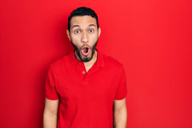 Sakallı, sıradan kırmızı tişörtlü İspanyol bir adam. Şaşırmış ve korkmuş bir ifade, korku ve heyecanlı bir yüz ifadesi var.. 