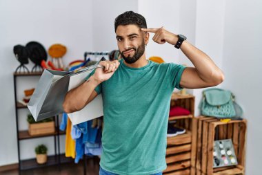 Satış mağazasında sakallı, alışveriş torbası tutan genç yakışıklı bir adam kendini vuruyor ve öldürüyor. Silah gibi el ve parmakları işaret ediyor, intihar jesti.. 