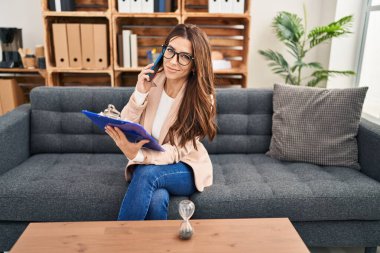 Psikoloji merkezindeki akıllı telefondan konuşan genç İspanyol kadın psikolog.