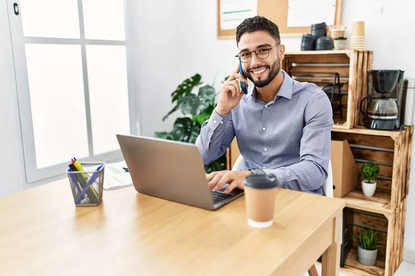 Mladý Arabský Muž Mluví Smartphone Pomocí Notebooku Pracuje Kanceláři — Stock fotografie