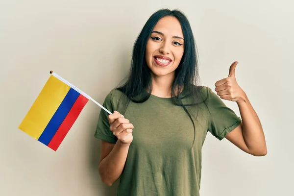 Młoda Latynoska Dziewczyna Trzyma Flagę Kolumbii Uśmiechnięta Szczęśliwy Pozytywny Kciuk — Zdjęcie stockowe