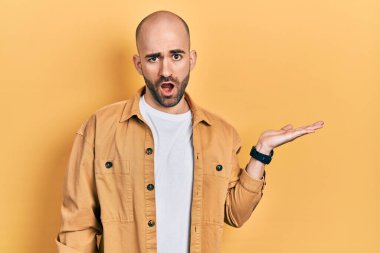 Genç kel adam avuçlarını açmış, şok olmuş bir yüz ifadesi takınıyor, şüpheci ve alaycı bakıyor, ağzı açık kalmış. 