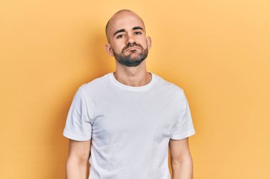 Genç kel bir adam günlük beyaz tişört giyiyor. Uykulu ve yorgun görünüyor. Yorgunluktan bitkin düşmüş ve akşamdan kalma.. 