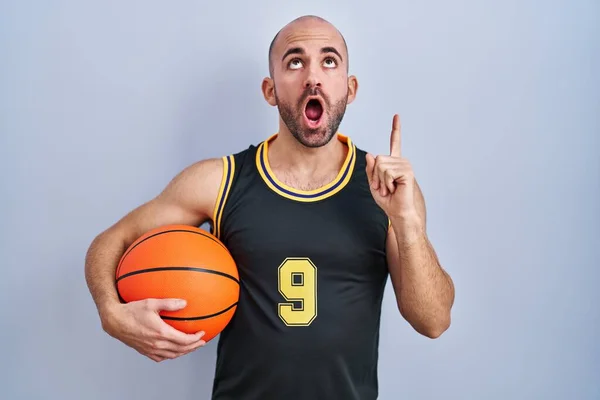 Joven Calvo Con Barba Vistiendo Uniforme Baloncesto Sosteniendo Pelota Asombrado — Foto de Stock