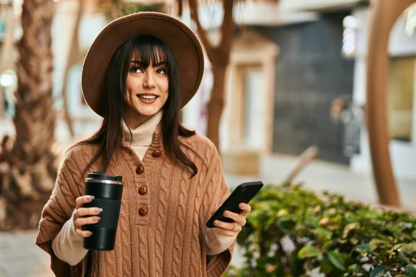 Brunetka Kobieta Czapce Zimowej Pomocą Smartfona Picia Filiżankę Kawy Świeżym — Zdjęcie stockowe