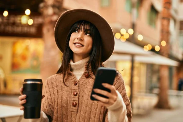 Brunetka Kobieta Czapce Zimowej Pomocą Smartfona Picia Filiżankę Kawy Świeżym — Zdjęcie stockowe