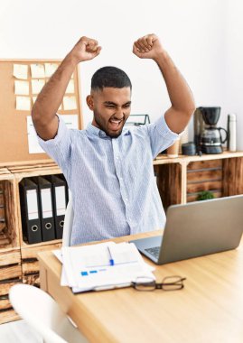 Genç Arap adam ofiste neşeli çalışıyor.