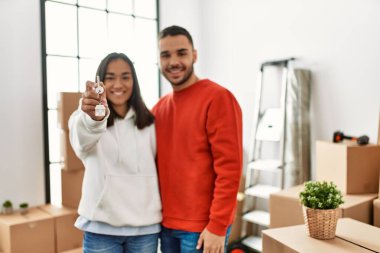 Genç İspanyol çift gülümsüyor mutlu bir şekilde yeni evin anahtarını tutuyor..