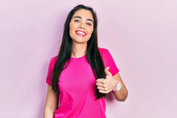 분홍색 티셔츠를 엄지손가락으로 스페인 소녀가 카메라 표정을 승인하는 이성공을 거둔다 — 스톡 사진