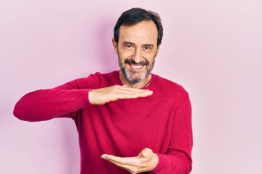 Orta yaşlı İspanyol bir adam, sıradan kıyafetler giyiyor. Elleriyle işaret ediyor. Ölçü sembolü. Kameraya bakıp gülümsüyor. ölçüm kavramı. 