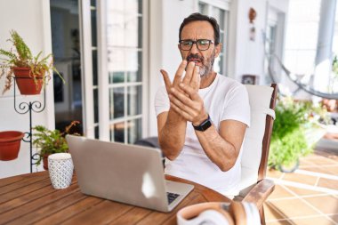 Orta yaşlı bir adam evde bilgisayar kullanıyor. Ellerinde ve parmaklarında ağrı var. Eklem iltihabı. 