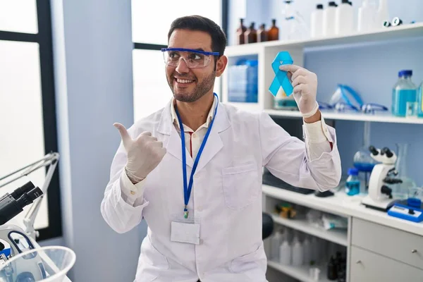 Young Hispanic Man Beard Working Scientist Laboratory Holding Blue Ribbon — Stock Photo, Image