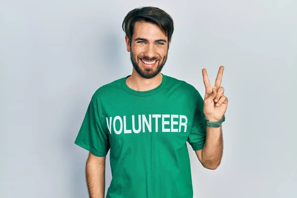 Jovem Hispânico Vestindo Camiseta Voluntária Sorrindo Olhando Para Câmera Mostrando — Fotografia de Stock