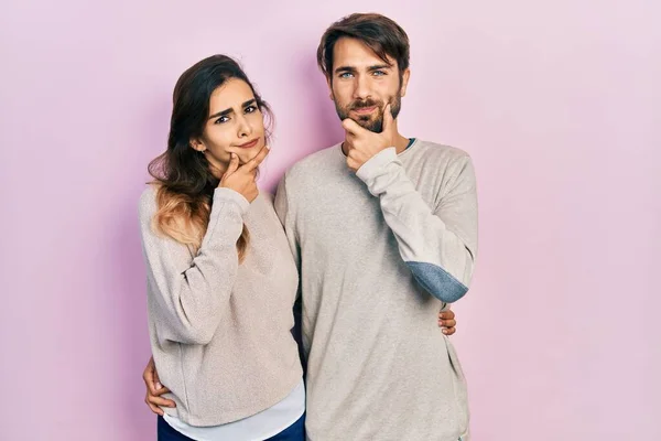 カジュアルな服を着ている若いヒスパニック系のカップルは カメラを見て自信を持って交差腕と手をあごに提起笑みを浮かべて ポジティブな — ストック写真