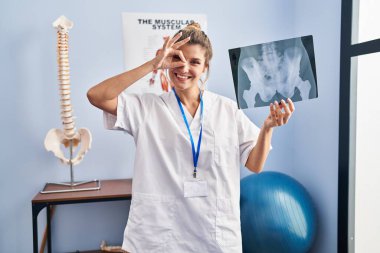 Elinde leğen kemiği radyografisi olan genç bir kadın gülümsüyor. 