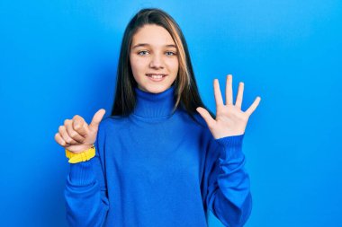 Balıkçı yaka kazak giyen genç esmer kız altı numarayı gösterip işaret ederken kendinden emin ve mutlu bir şekilde gülümsüyor.. 