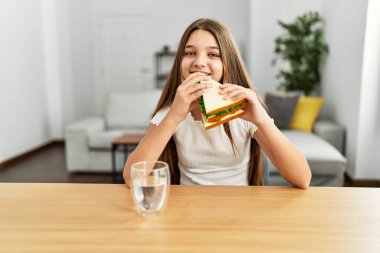 Evdeki masada kendinden emin gülümseyen sevimli kız.