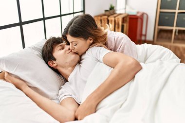 Beyaz bir kadın gülümsüyor. Mutlu bir şekilde erkek arkadaşını öpücükle uyandırıyor..