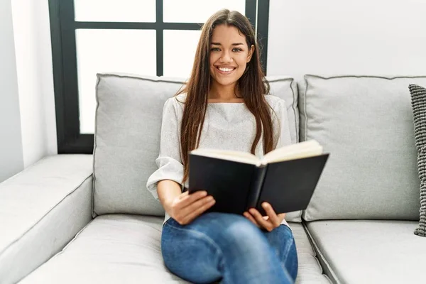 Νεαρή Λατίνα Γυναίκα Διαβάζει Βιβλίο Κάθεται Στον Καναπέ Στο Σπίτι — Φωτογραφία Αρχείου